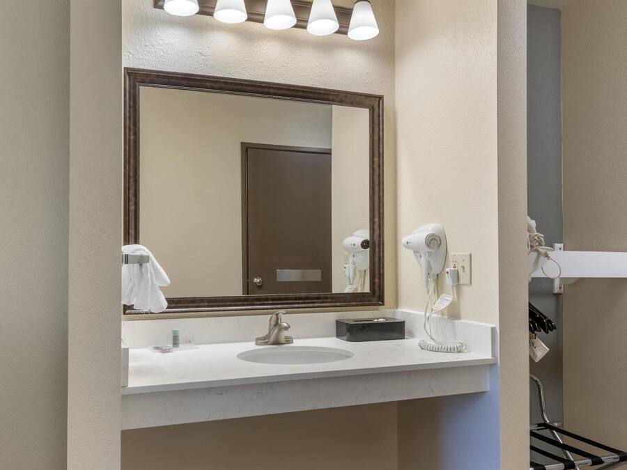 A bathroom with a large mirror, a sink, a hairdryer, and a towel rack.