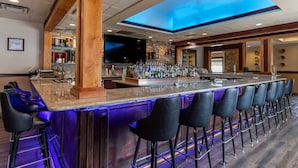 A bar area with a long counter, multiple stools, and a ceiling skylight.