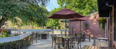 Un patio al aire libre con una mesa y sillas, rodeado por una barandilla y árboles.