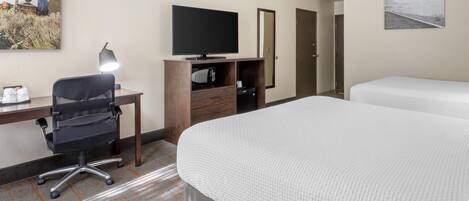 A hotel room with a desk, office chair, television, two beds, and artwork on the walls.