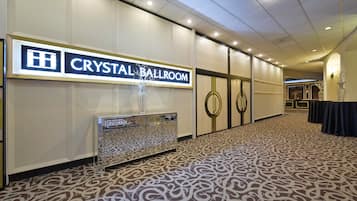 Un pasillo de hotel con un letrero que dice "Crystal Ballroom", un piso con estampado y una zona de recepción con una vitrina de cristal.