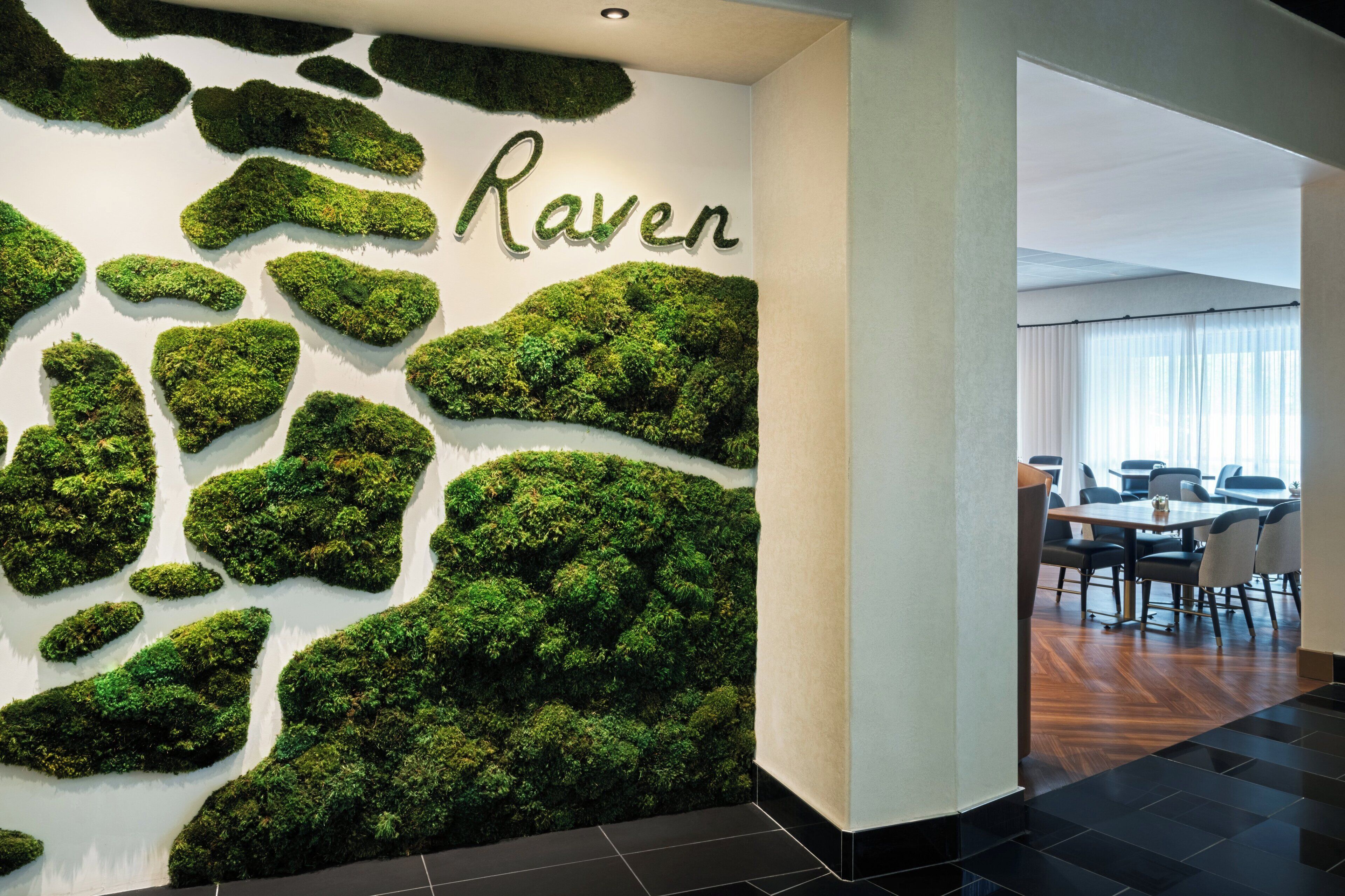 Een muur met een mosachtige textuur en het woord 'Raven' in een gestileerd lettertype.