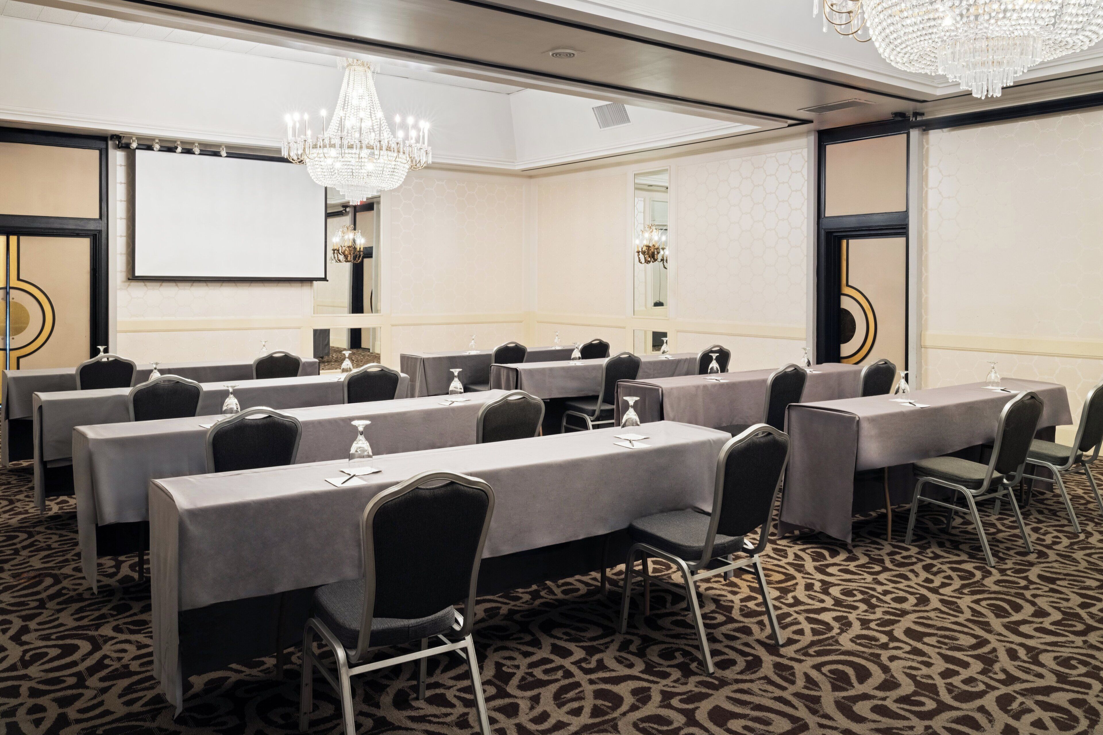 A conference room with long tables, chairs, and a chandelier.