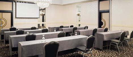 A conference room with long tables, chairs, and a chandelier.