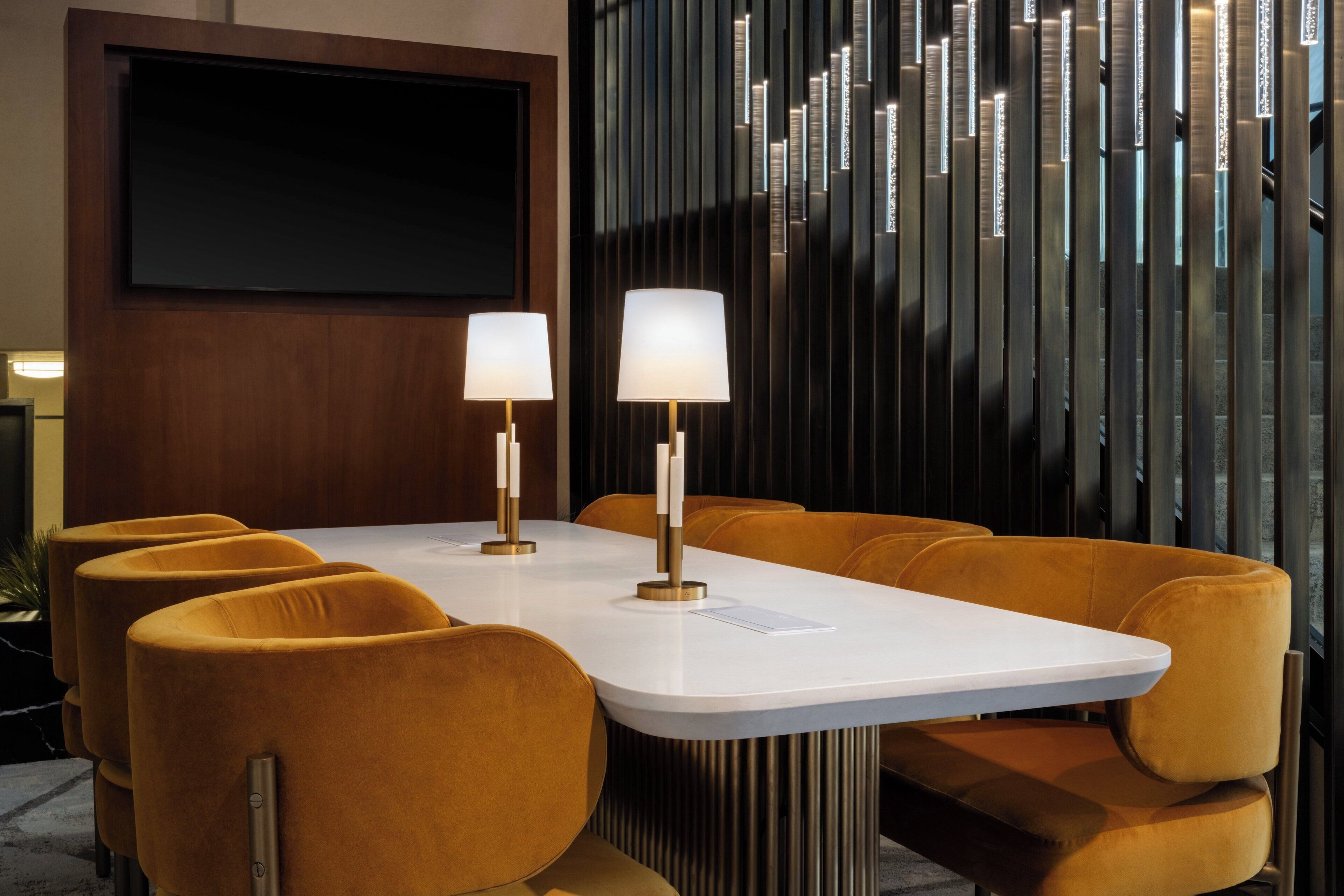 Une salle de conférence avec une table blanche, deux lampes et six chaises.