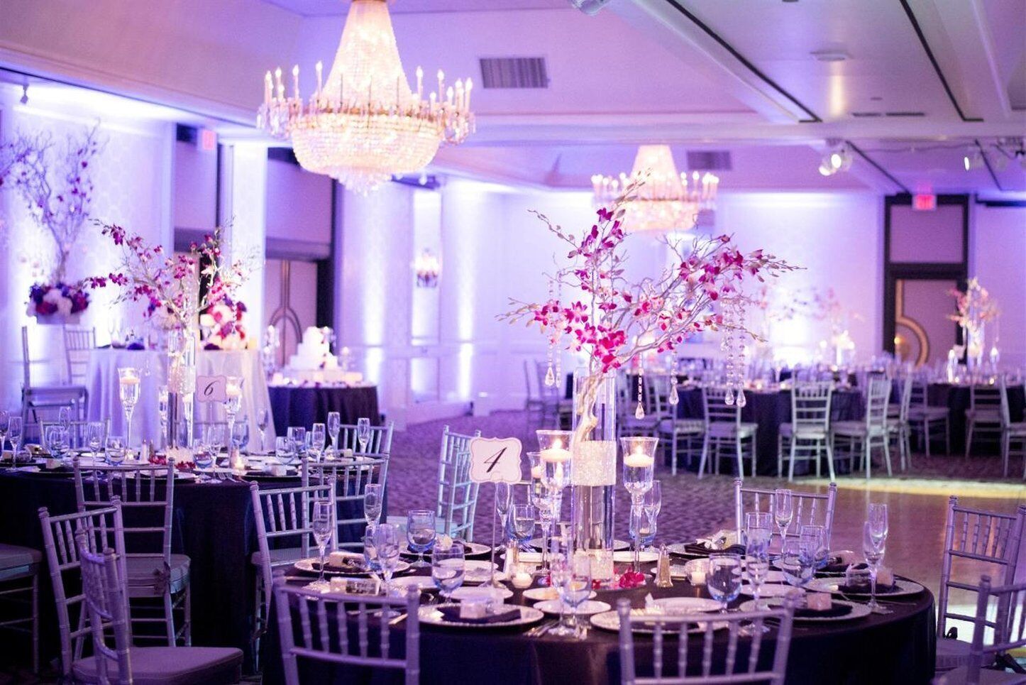 Un salón de banquetes con mesas redondas, sillas y centros de mesa florales.
