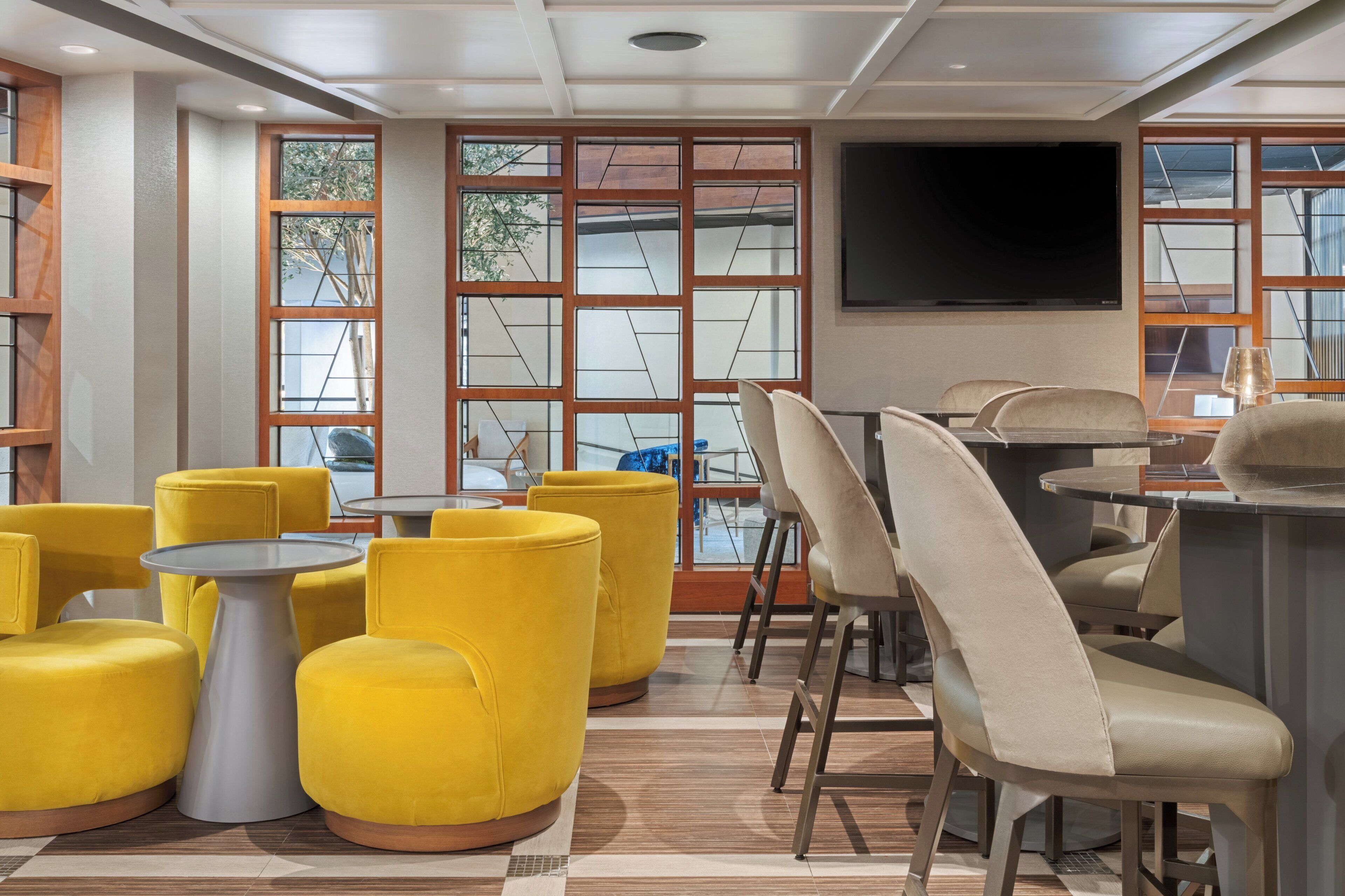 A modern interior with yellow chairs, a bar area, and large windows with a view.