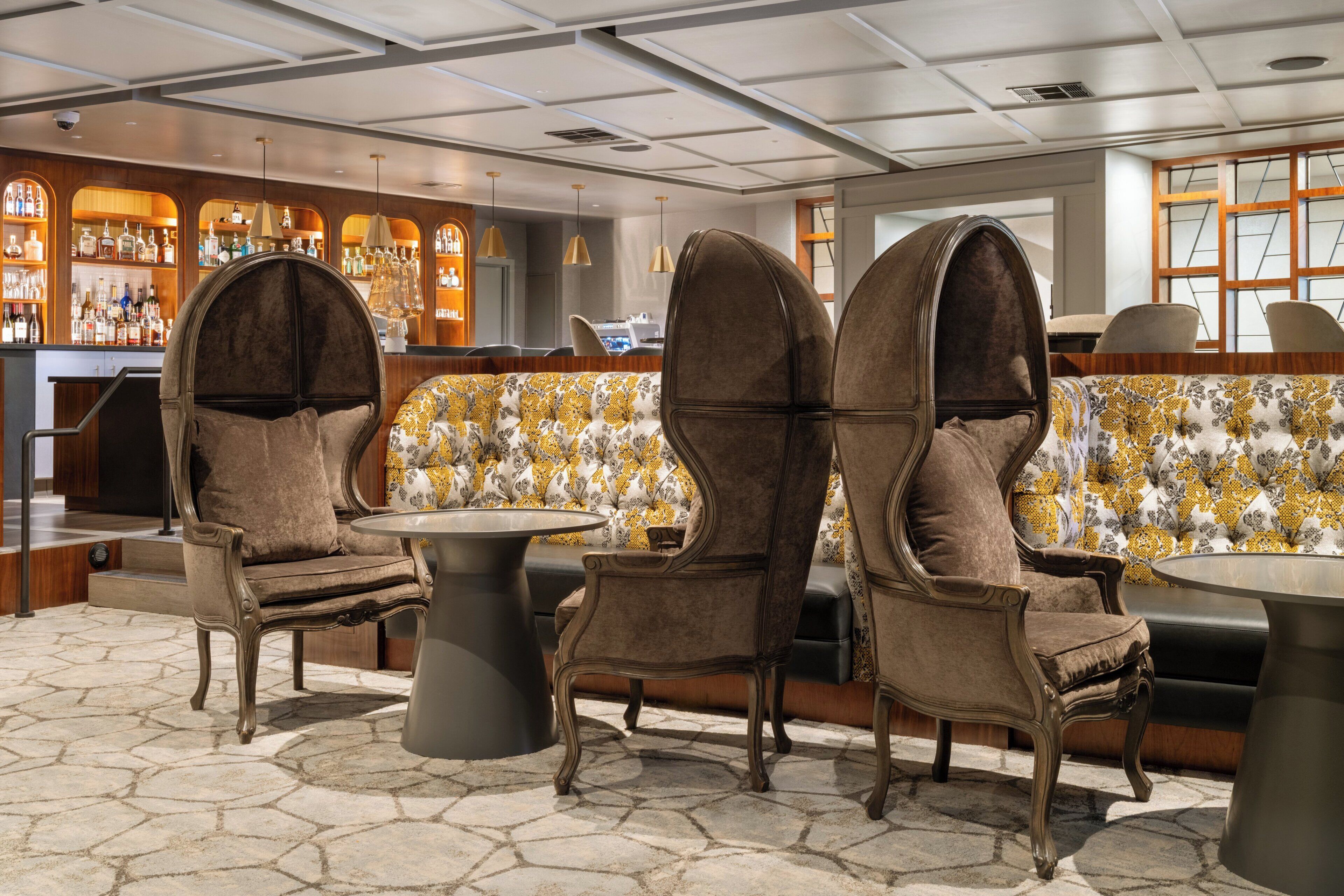 A bar area with high-backed chairs, a round table, and a patterned sofa.
