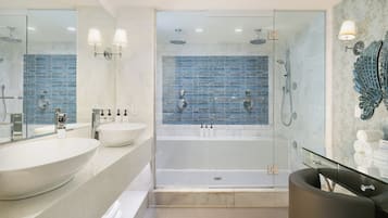 A modern bathroom with a glass-enclosed shower, two sinks, and a vanity.