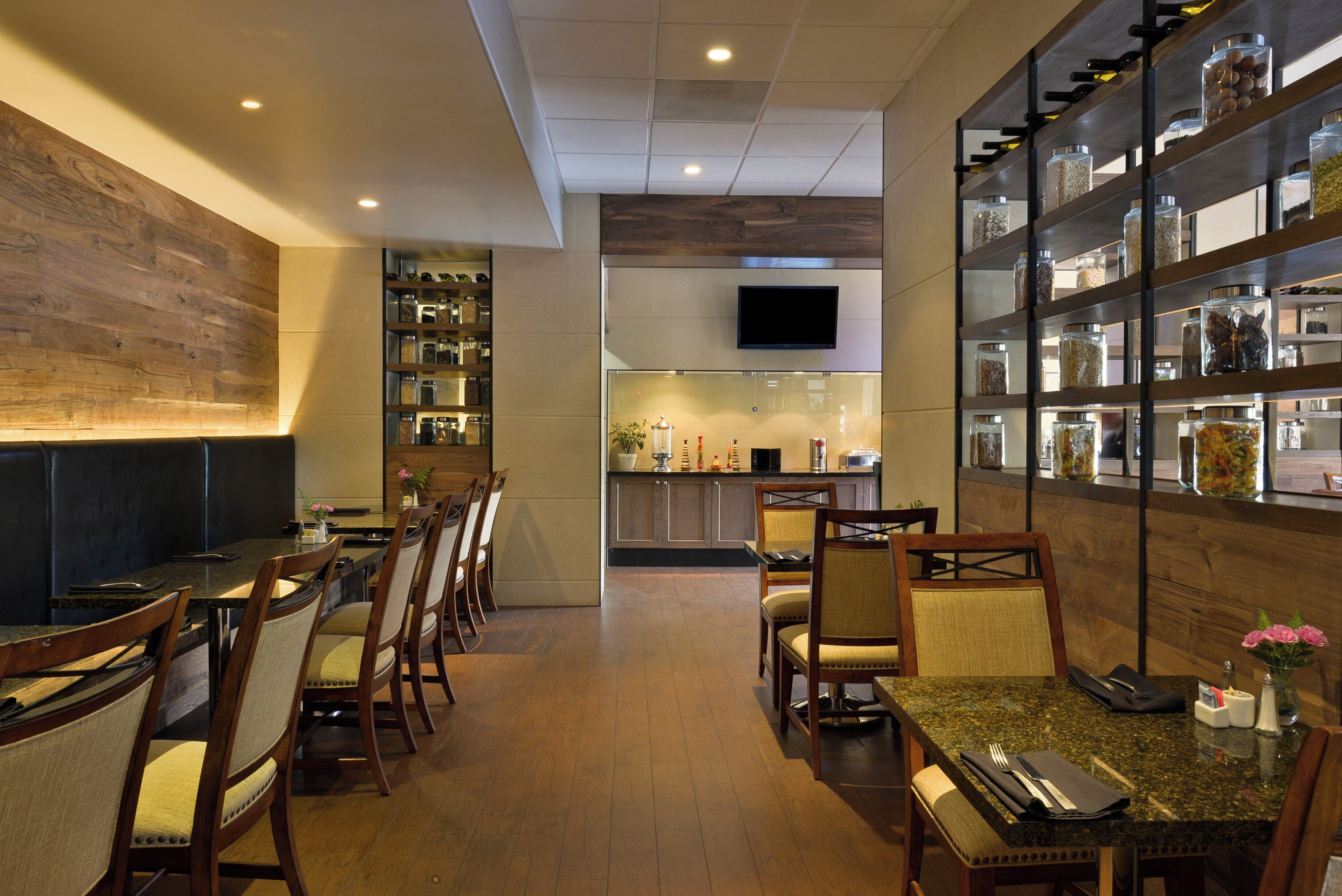 Interior de restaurante con mobiliario de madera, una zona de bar y una cocina al fondo.