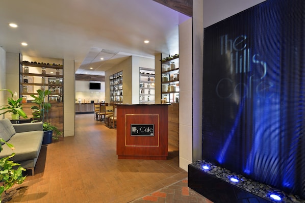 A hotel lobby with a reception desk, seating area, and shelves with items.