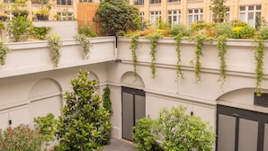 A courtyard with a central planter, potted plants, and a building with multiple balconies. - Crowne Plaza Paris Republique by IHG (Paris)