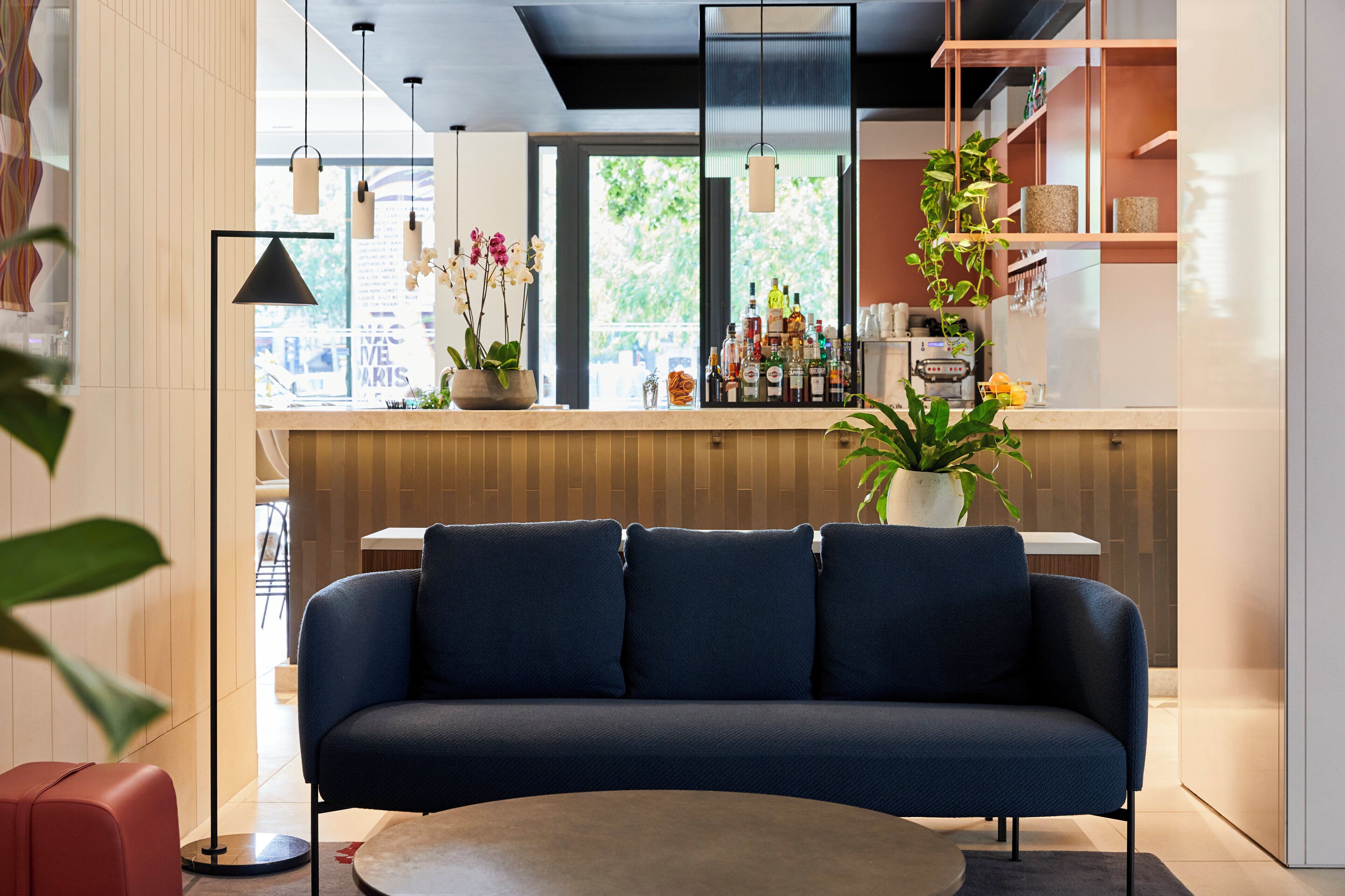 A modern interior with a sofa, a coffee table, and a bar area with various bottles.