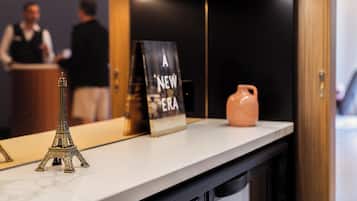 A reception desk with a small Eiffel Tower model, a sign reading "A NEW ERA," and a pink vase.