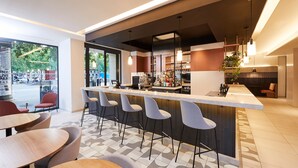 A modern bar area with a long counter, multiple bar stools, and a seating area with round tables. - Crowne Plaza Paris Republique by IHG (Paris)