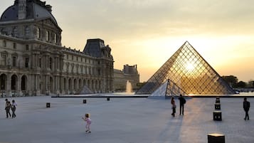 A large open plaza with a prominent glass pyramid and classical architecture in the background.