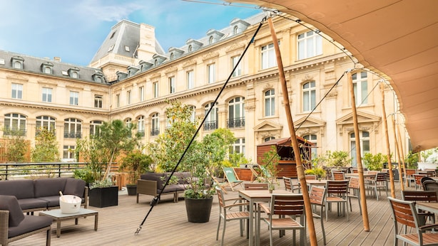 An outdoor terrace with wooden flooring, tables, chairs, and potted plants. - Crowne Plaza Paris Republique by IHG (Paris)