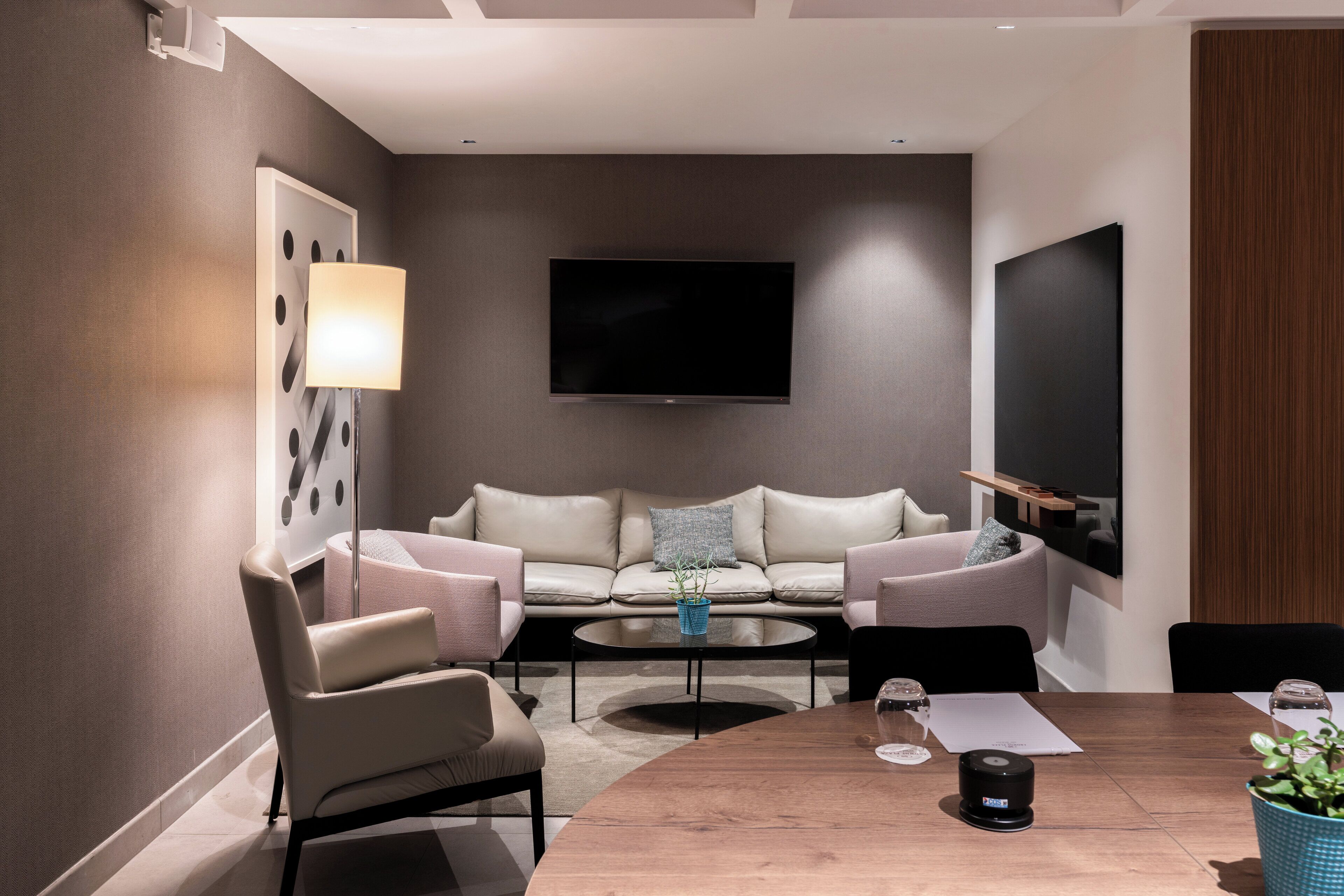 Ein modernes Wohnzimmer mit Sofa, Couchtisch und einem flachbildfernseher an der Wand.