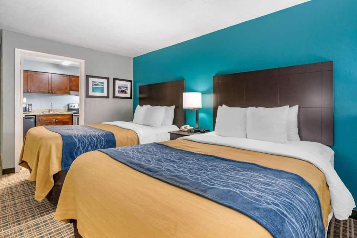 Una habitación de hotel con dos camas, kitchenette y baño.