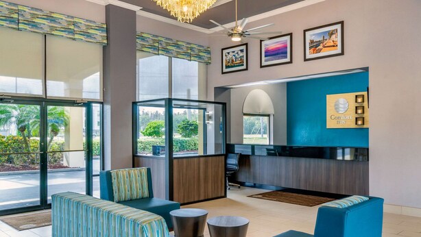 A hotel lobby with seating areas, a reception desk, and large windows offering views of the outdoors. - Comfort Inn Sun City Center - Ruskin - Tampa South (Sun City Center)