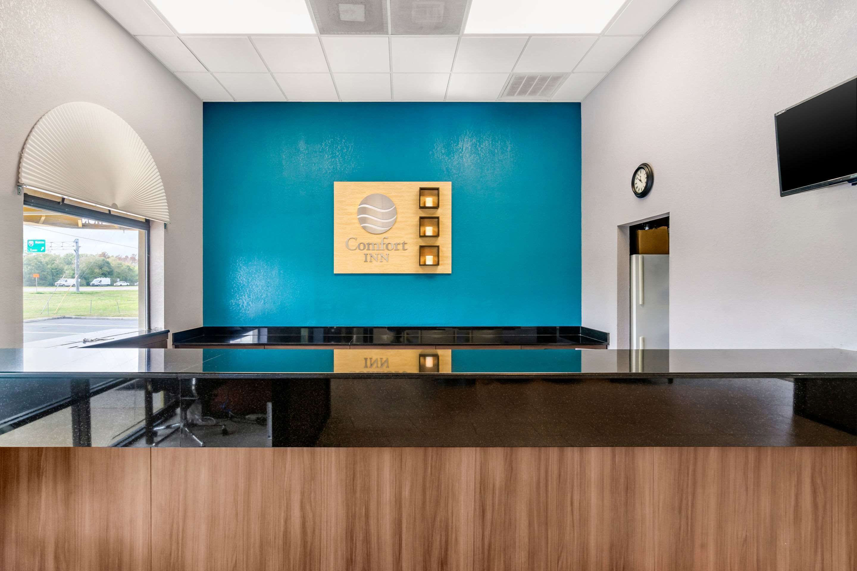 A reception desk with a blue wall and a Comfort Inn sign.