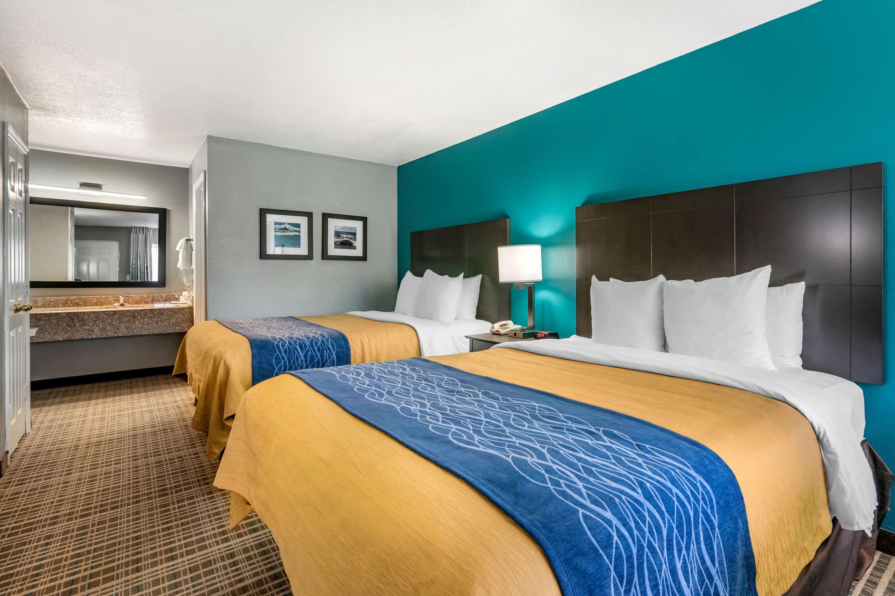 A hotel room with two beds, a bathroom, and a view of the city.