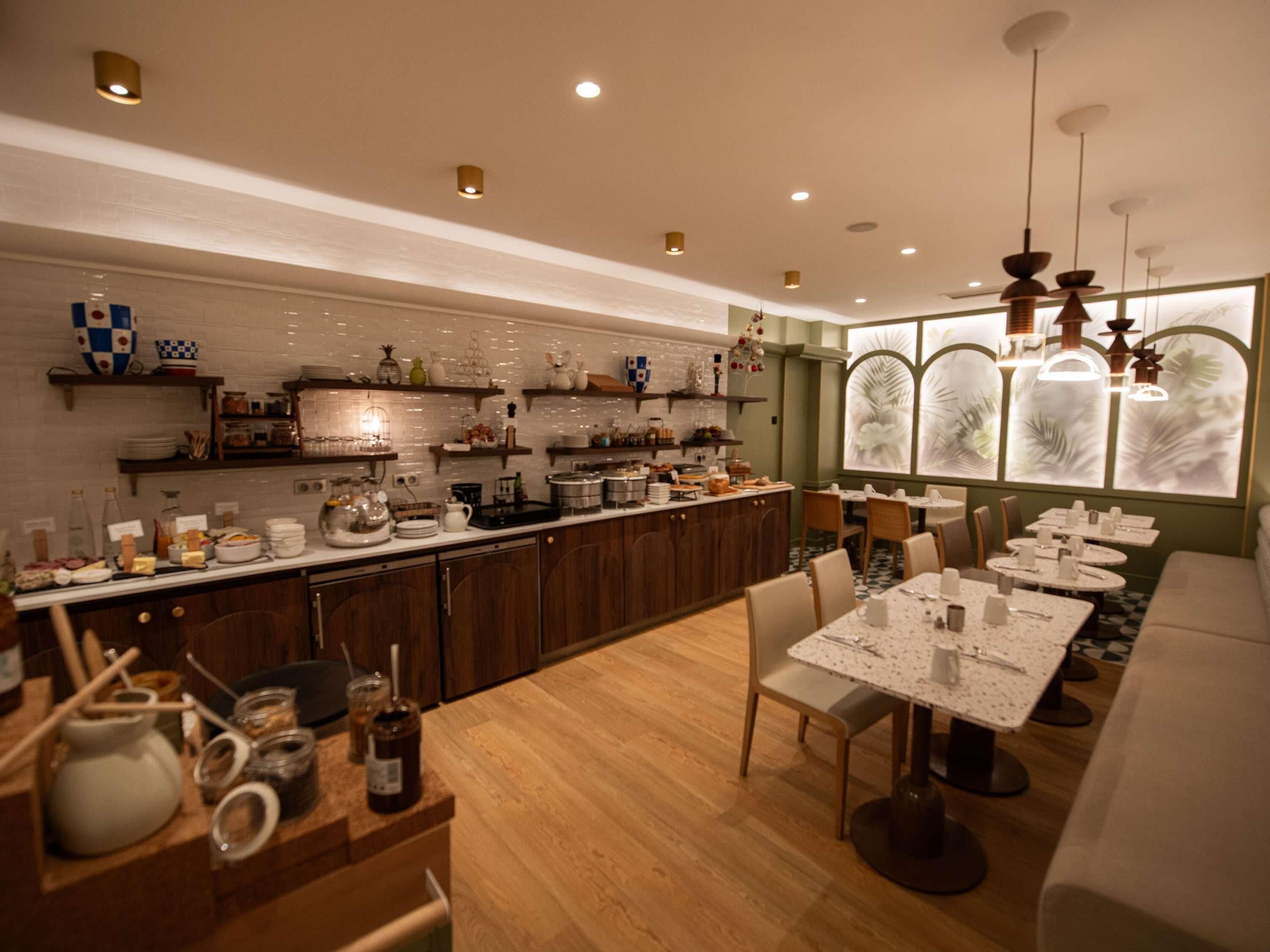 A modern kitchen with wooden cabinets, a central island, and a dining area with round tables.