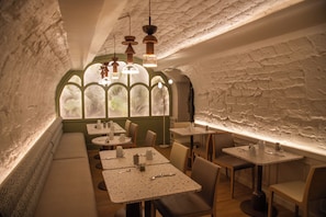 A restaurant with a rustic interior, featuring exposed brick walls, arched windows, and a variety of seating arrangements including tables and benches. - Mercure Paris Opera Grands Boulevards (Paris)