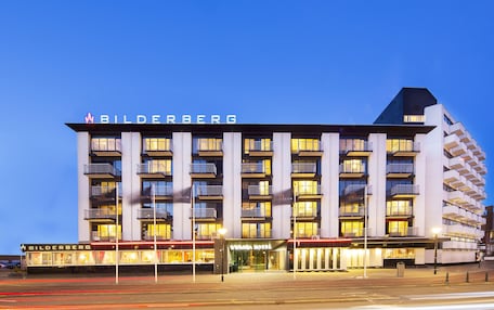 A multi-story hotel with a modern design, featuring balconies and a prominent signage.