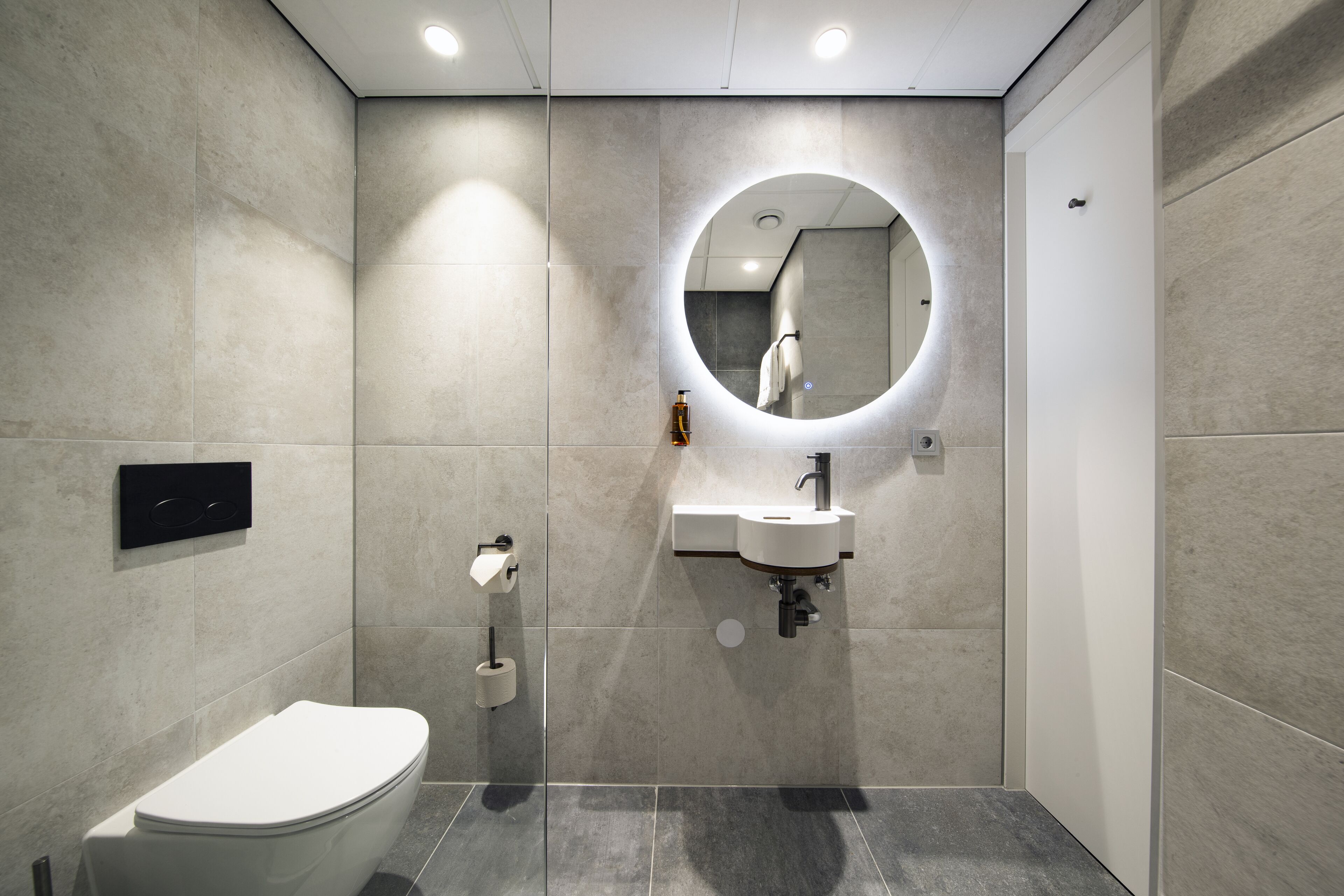 A modern bathroom with a toilet, sink, and mirror.