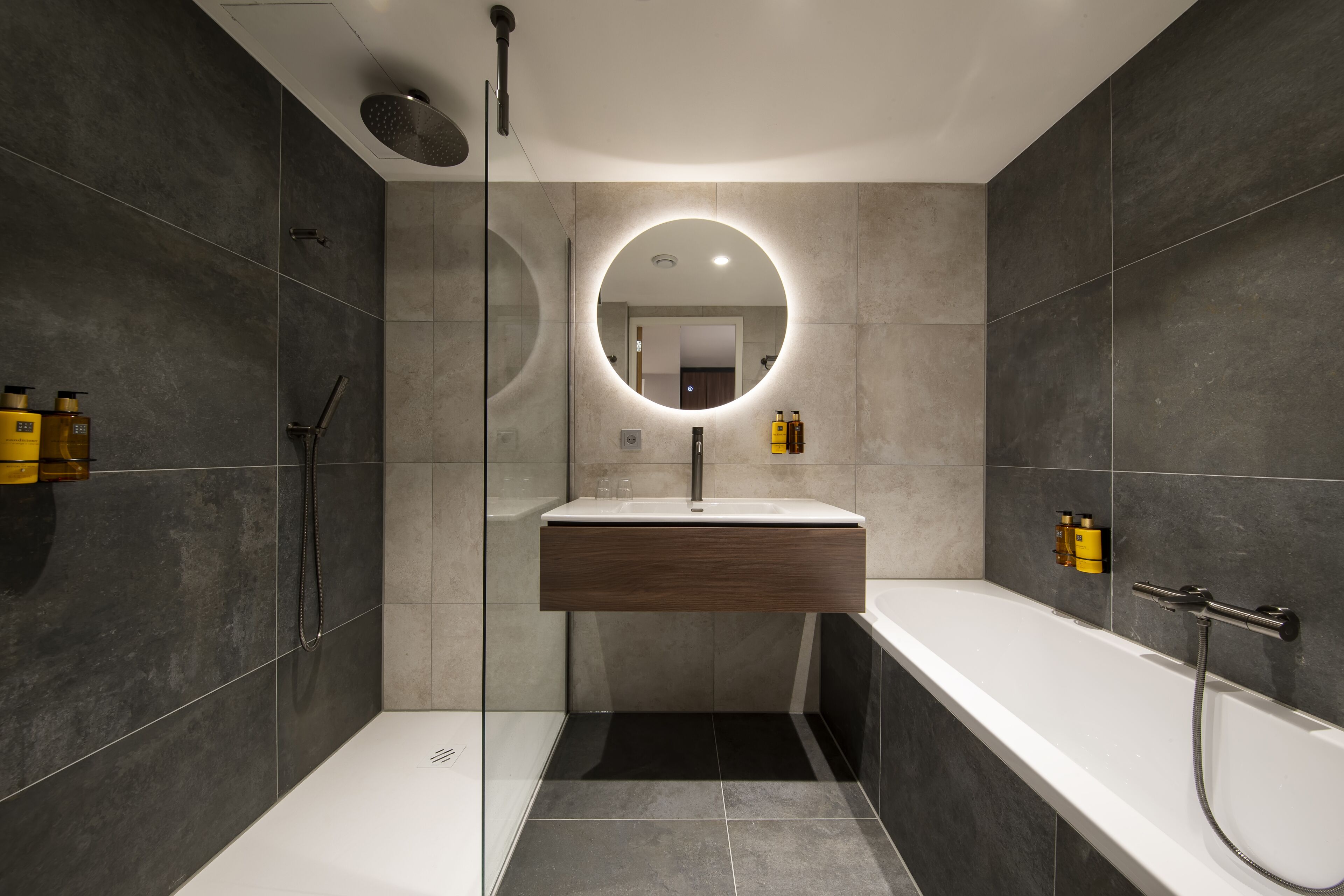 A modern bathroom with a glass-enclosed shower, a freestanding bathtub, and a vanity with a mirror.