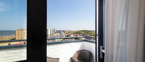 A balcony with a view of the sea and buildings.