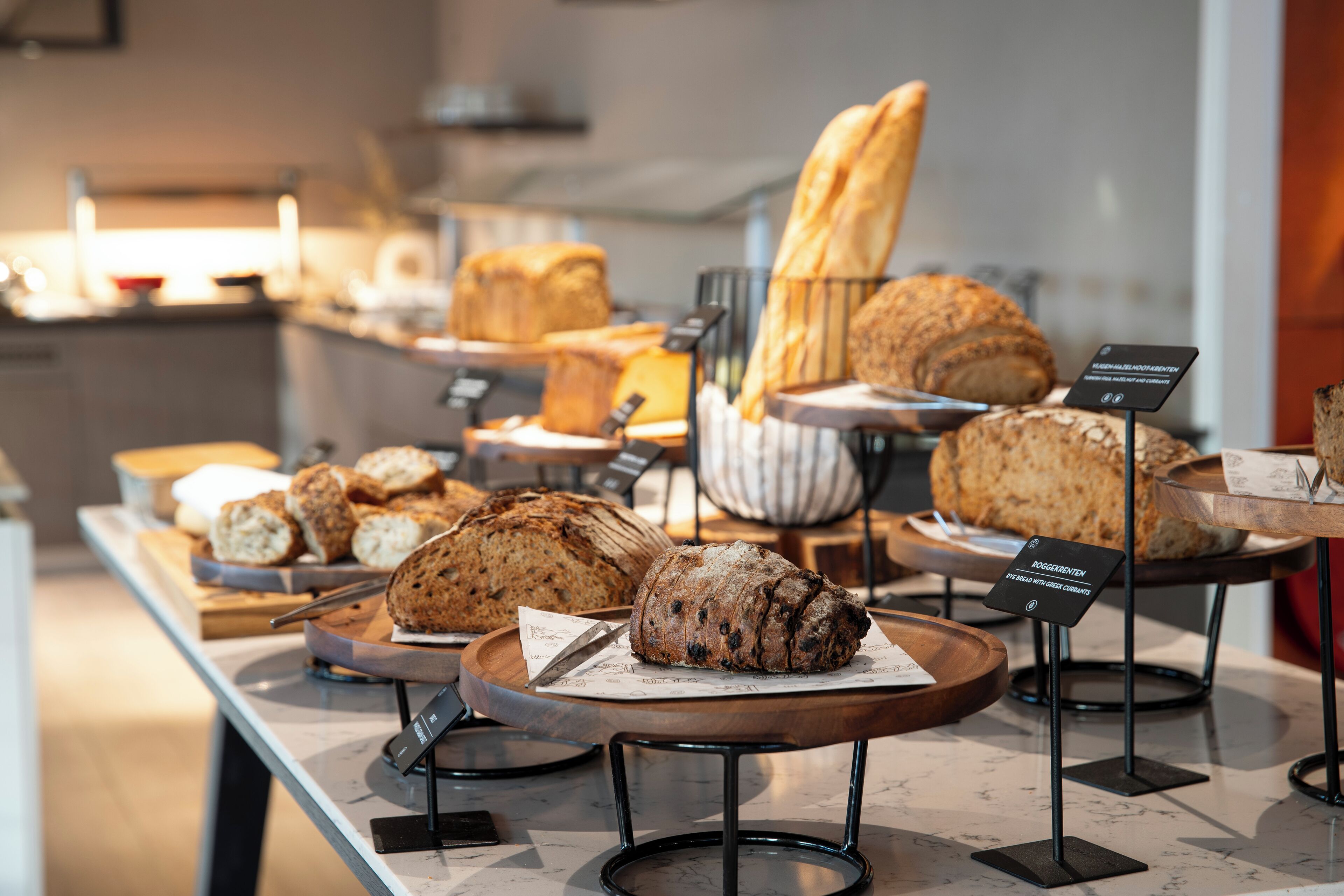 Exposição de pães e doces numa padaria, em suportes de madeira.