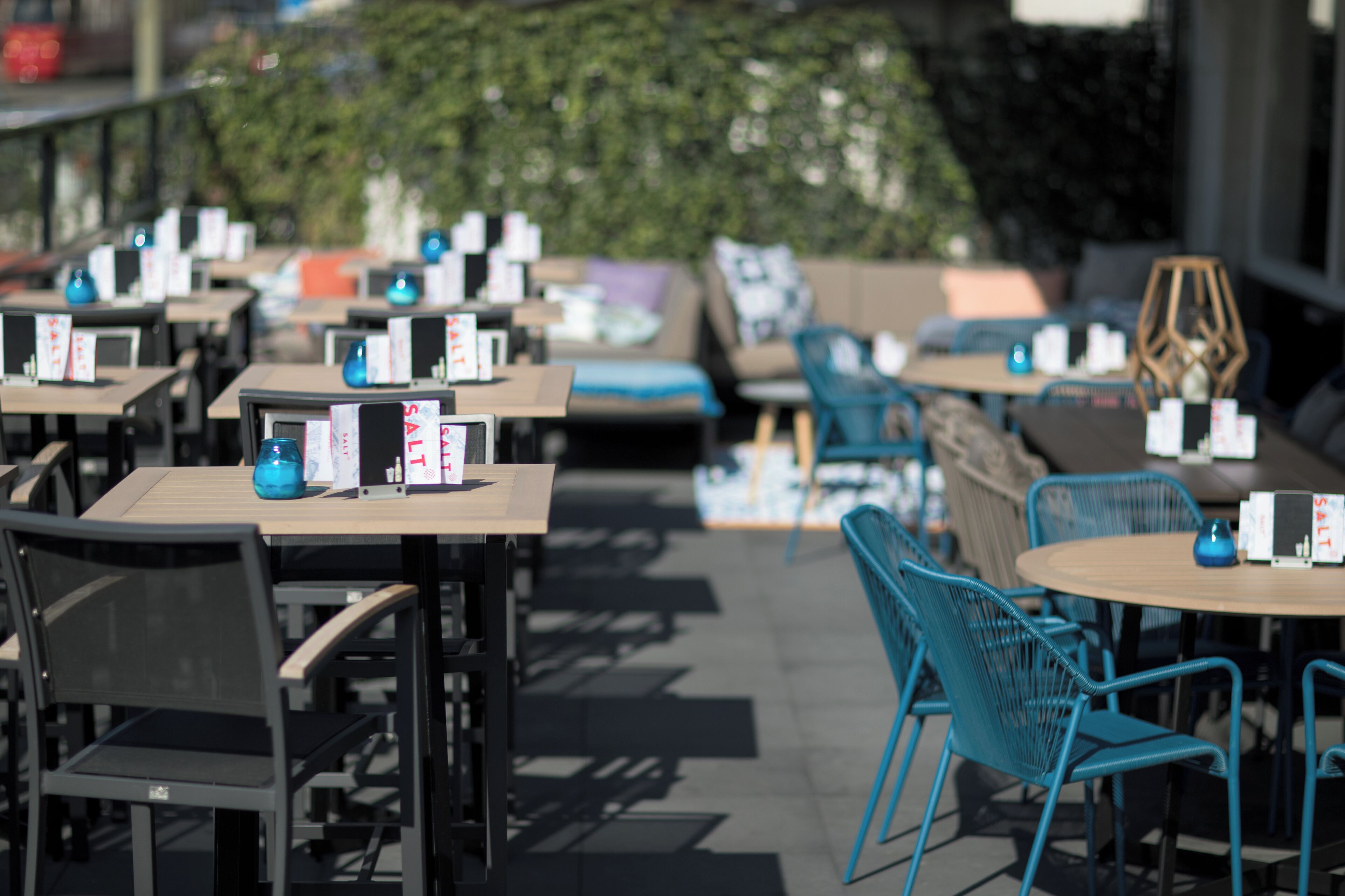 An outdoor seating area with tables and chairs, some with menus on them.