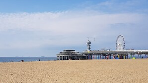 Une jetée avec une grande roue et un bâtiment doté d’une tour.