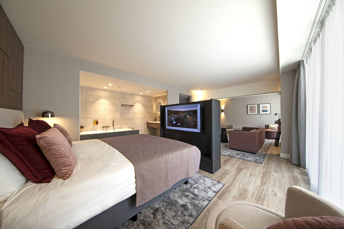 Een moderne hotelkamer met een groot bed, een televisie, een badkamer en een zithoek.
