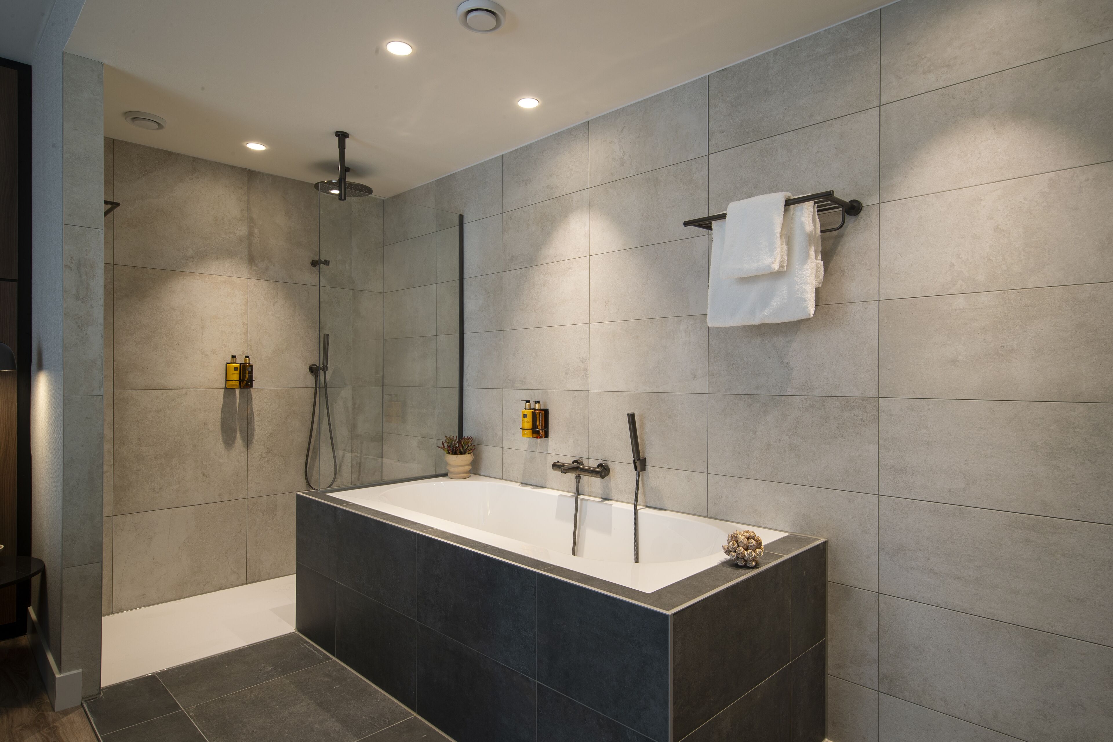 Un baño moderno con una bañera independiente, un cabezal de ducha y un perchero para toallas.
