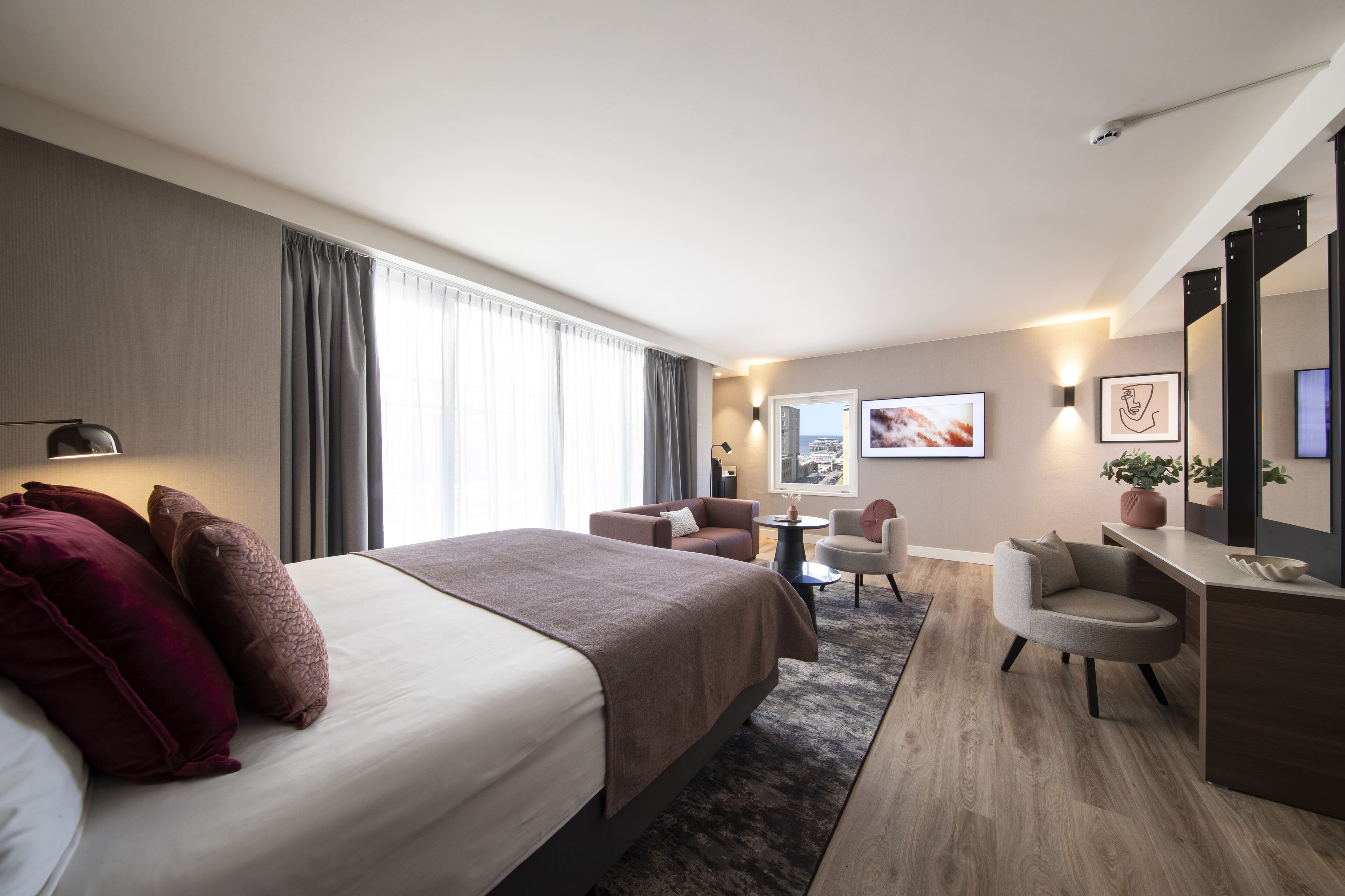 Een moderne hotelkamer met een groot bed, een bureau, een stoel en een kleine tafel.
