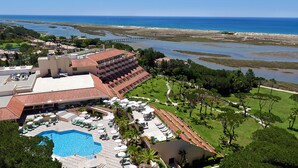 A resort with a swimming pool, sun loungers, and a view of the ocean.
