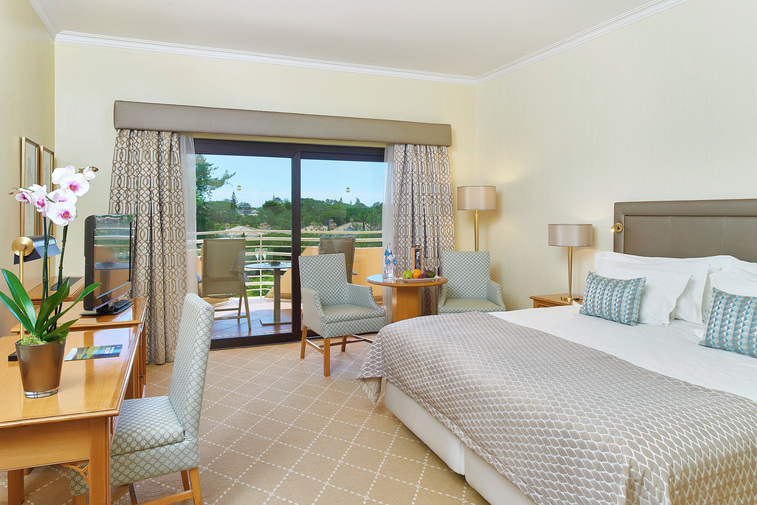 Una camera d'albergo con un letto, due poltrone, una scrivania, una televisione e vista sull'esterno.