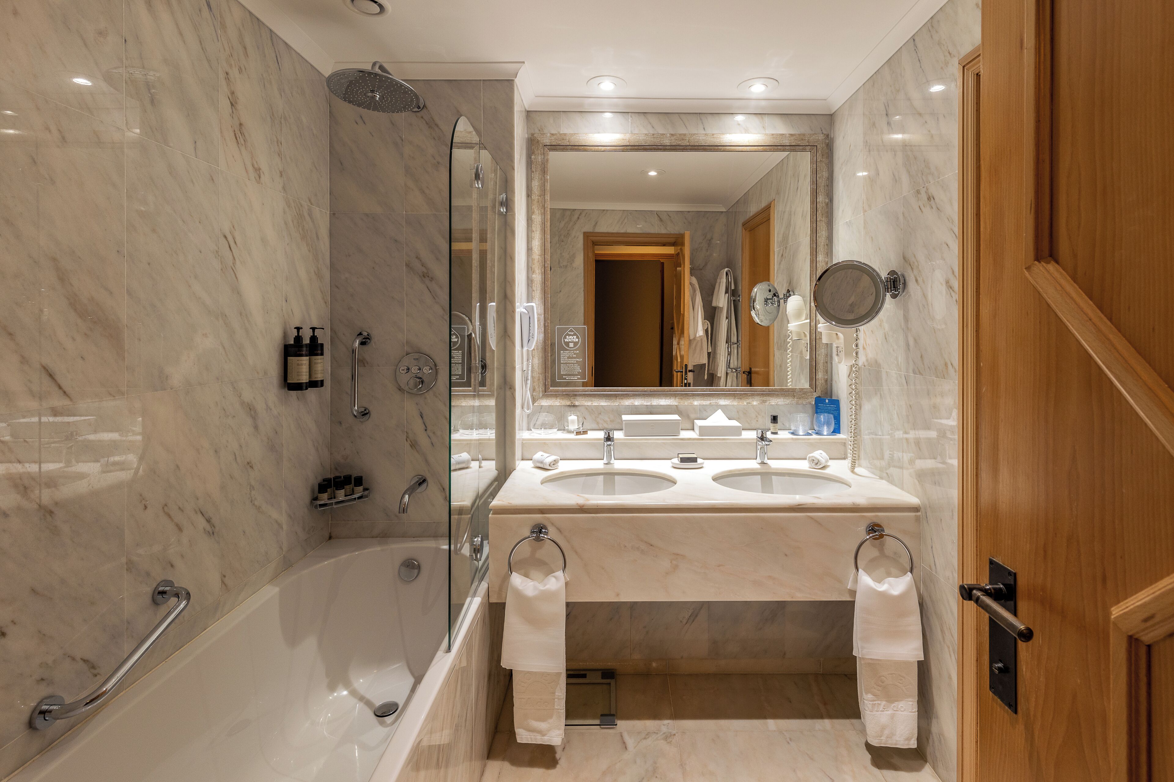 A modern bathroom with a bathtub, two sinks, and a shower.