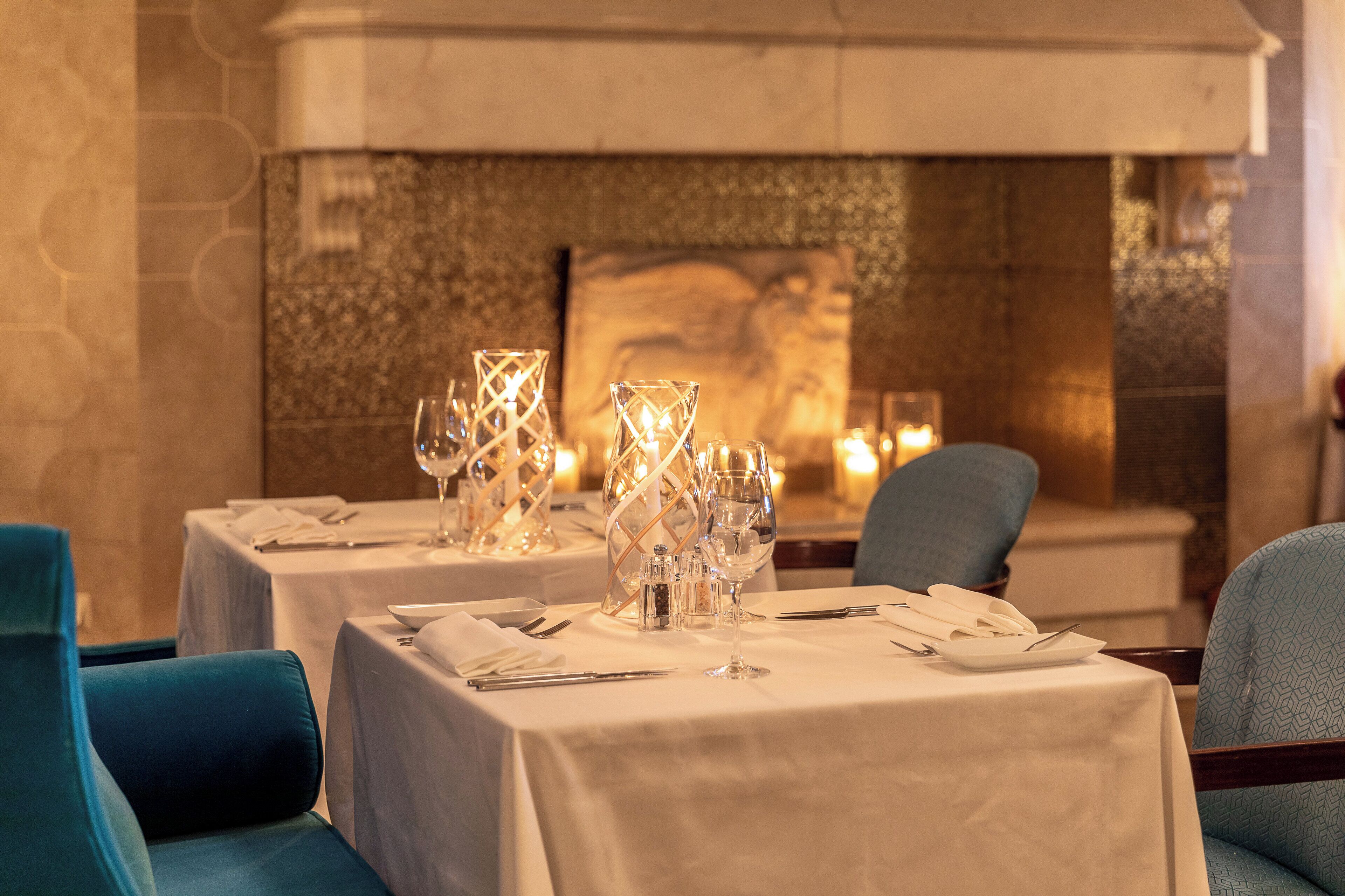A dining area with tables set for two, featuring clear glassware and napkins.
