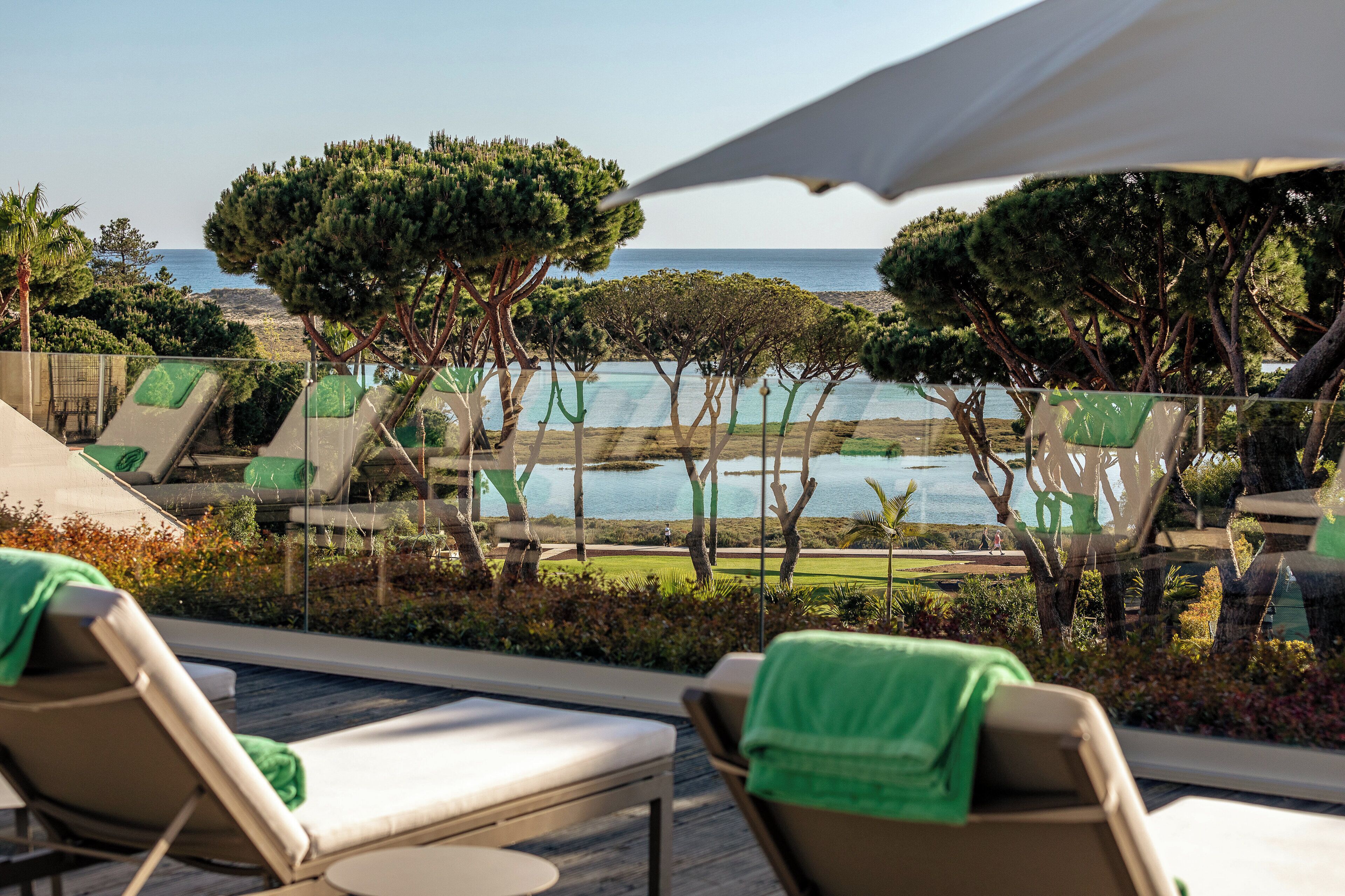 A poolside area with lounge chairs and a view of the sea.