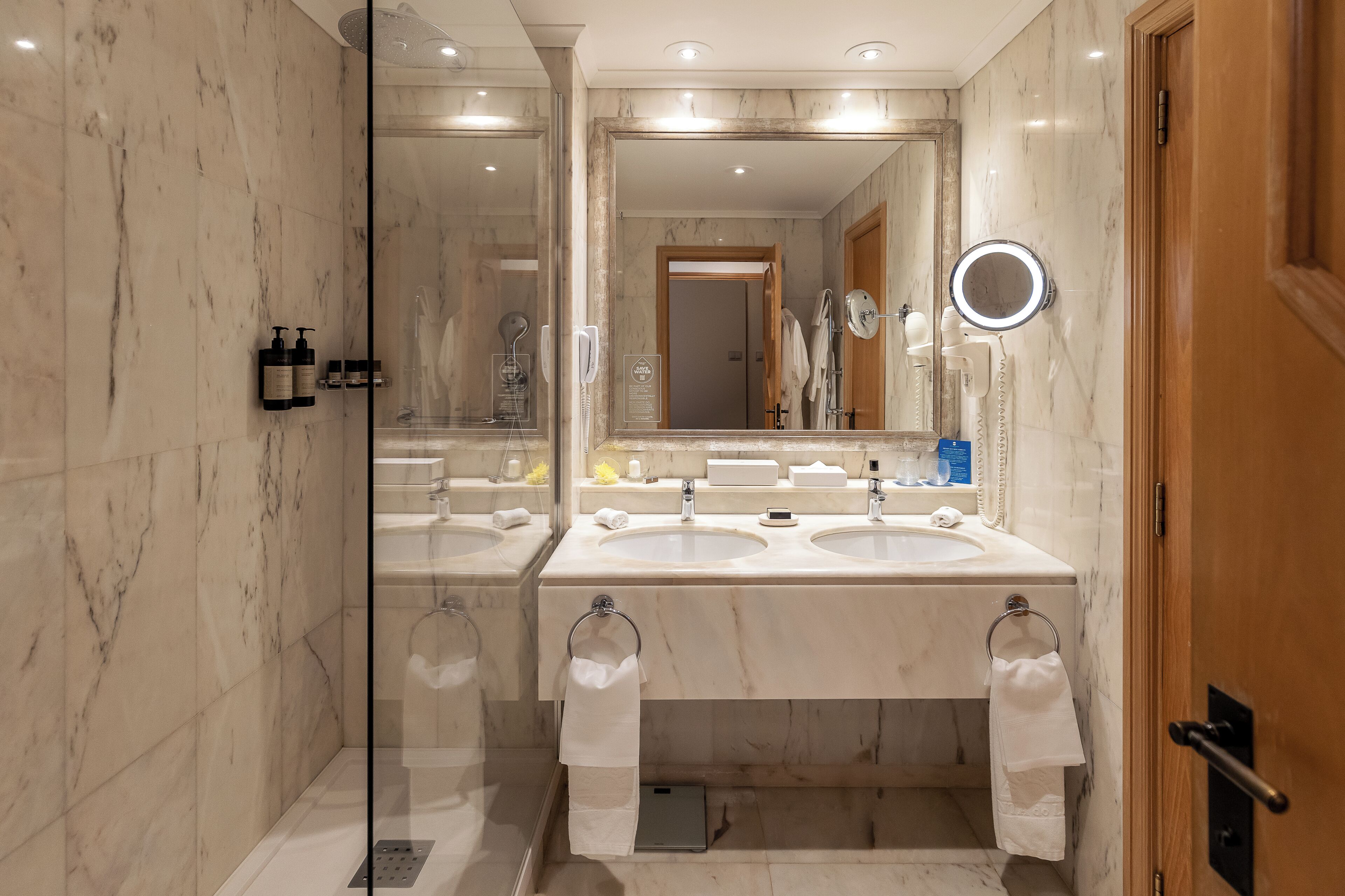 A bathroom with two sinks, a glass shower enclosure, and a wooden door.