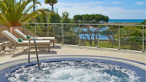 Un jacuzzi doté d’une balustrade en verre, de chaises longues et offrant une vue sur la mer.