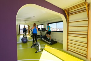 Un gimnasio con cintas de correr, una bicicleta estática y pelotas de ejercicio.