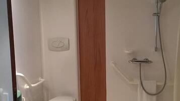 A small, modern bathroom with a toilet, a shower, and a wooden accent wall.