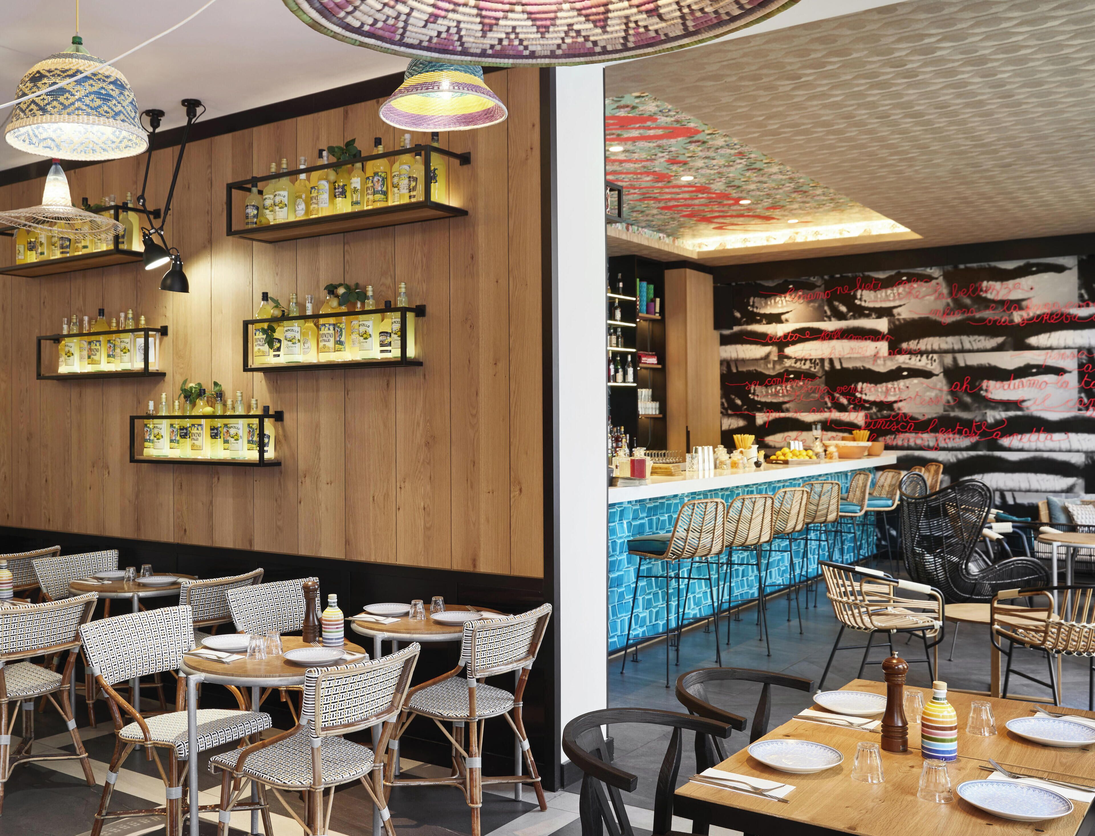 A restaurant interior with wooden panel walls, hanging pendant lights, and a bar area with stools and a counter.