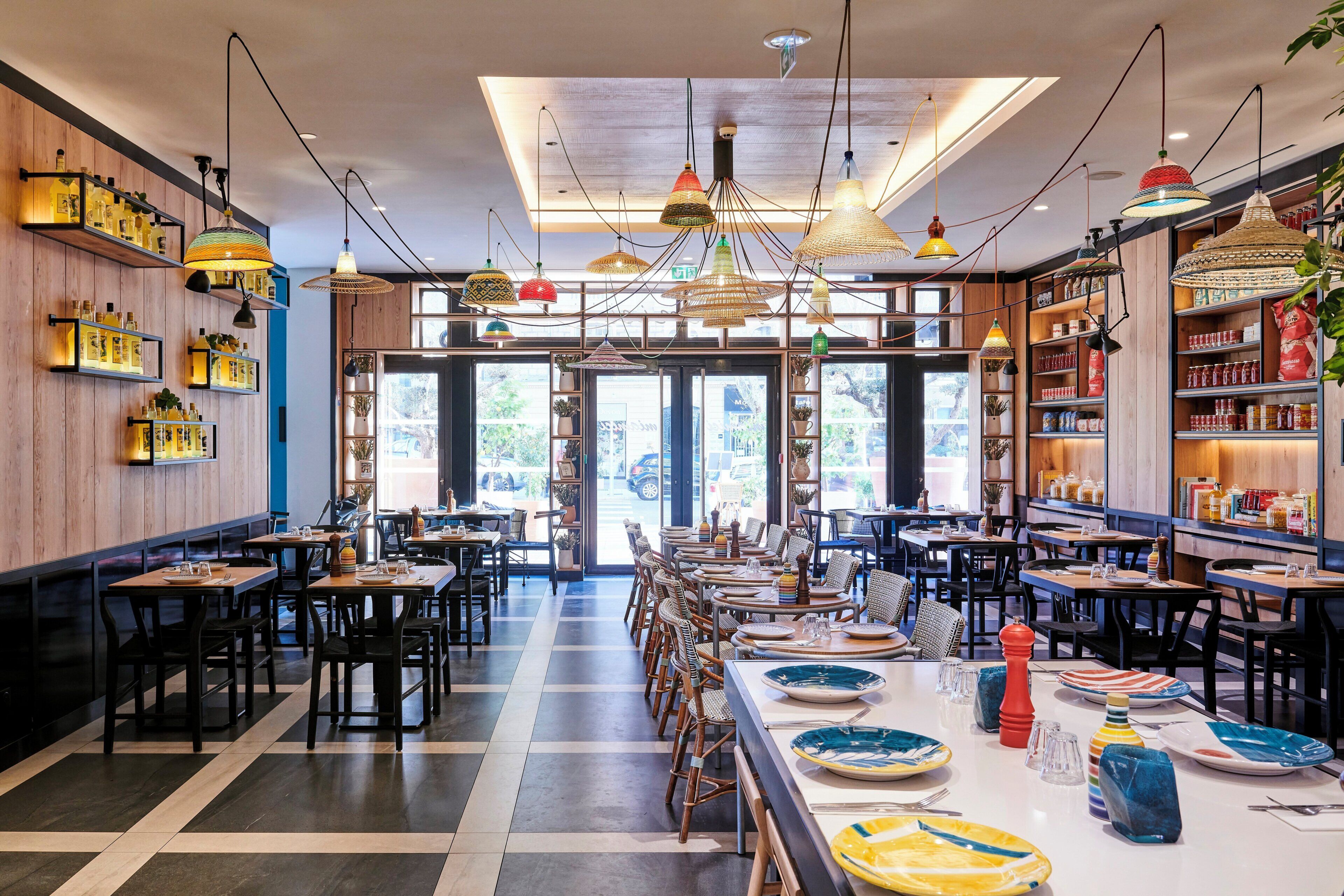 L’intérieur d’un restaurant, avec de nombreuses tables, des chaises et des luminaires suspendus.