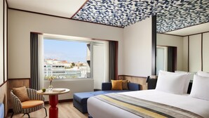 Habitación de hotel con una cama grande, un sofá, una mesita y vistas a edificios.